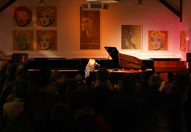 Der Blues-Pianist Pete Buden vor der Kulisse großformatiger Bilder aus Gummibärchen des Künstlers Johannes Cordes
